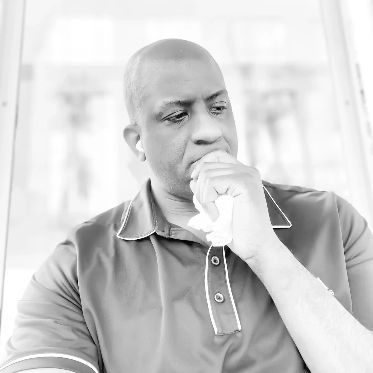 Man in deep thought holding a tissue.