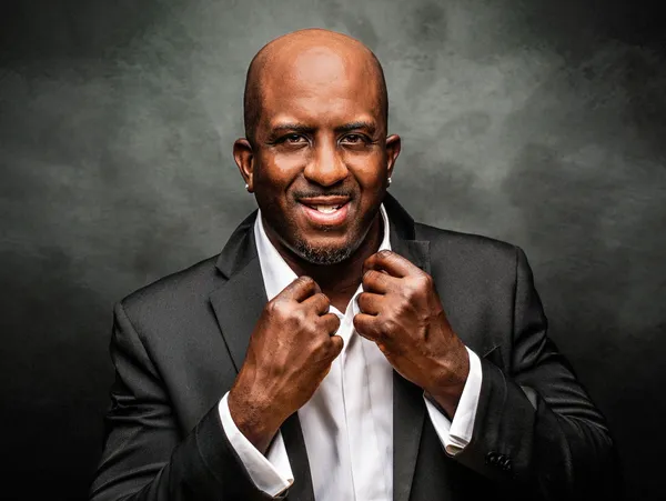 Smiling man in formal attire, dark background